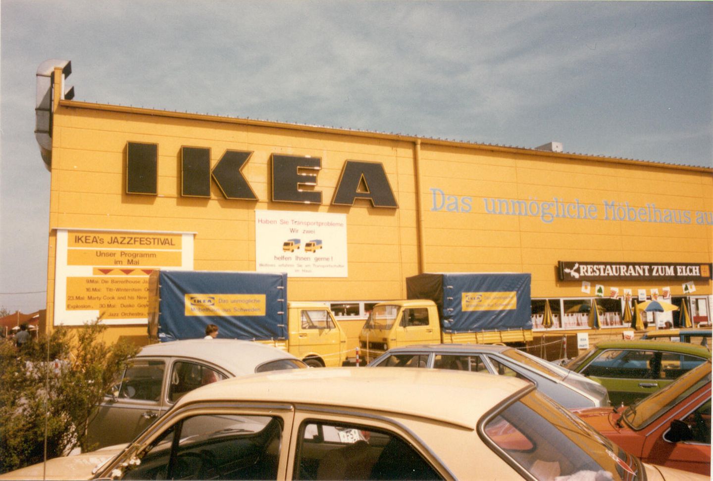 Gelbe Fassade eines Ikea-Möbelhauses, davor zwei Lieferwagen und parkende Autos