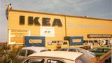Gelbe Fassade eines Ikea-Möbelhauses, davor zwei Lieferwagen und parkende Autos