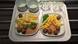 Tablett, darauf zwei Teller mit Hackbällchen, Pommes, Erbsen sowie Becher und Gläser
