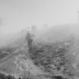 Schwarz-weiß Fotografie: Menschen laufen durch Nebel einen Hügel hinauf