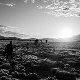 Schwarz-weiß Fotografie: Menschen laufen durch eine Hochebene in den Anden