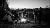 Schwarz-weiß Fotografie: Männer stehen um eine Feuerstelle