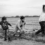 Schwarz-weiß Fotografie: Mutter und zwei Kinder laufen angestrengt durch tiefen Schlamm