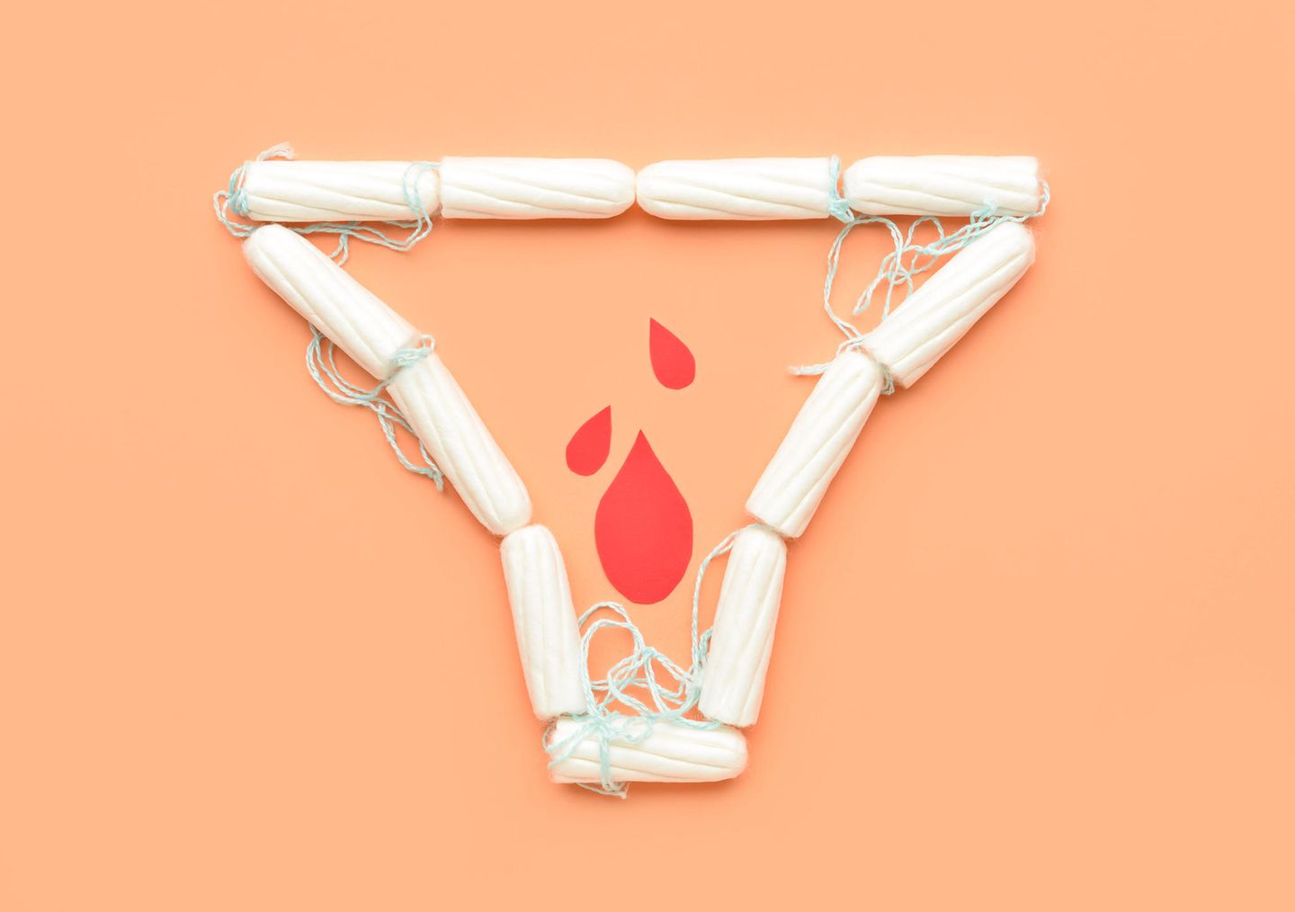 Tampons auf orangefarbenen Hintergrund in Form eines Slips mit Blutstropfen aus Papier innerhalb der Slipform.