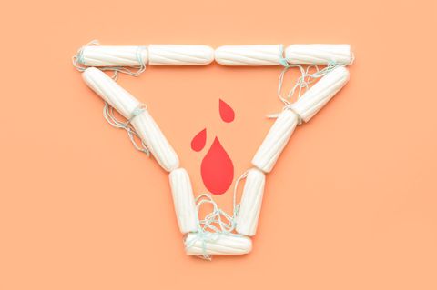 Tampons auf orangefarbenen Hintergrund in Form eines Slips mit Blutstropfen aus Papier innerhalb der Slipform.