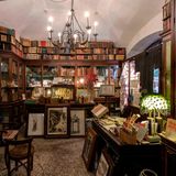 Regale voller Bücher in einem alten Raum, darüber hängt ein Leuchter