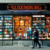 Schaufenster voller Bücher, zwei Menschen gehen vorbei