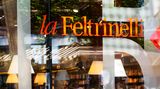 Blick durchs Schaufenster, Menschen trinken Kaffee, dahinter Buchregale