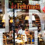 Blick durchs Schaufenster, Menschen trinken Kaffee, dahinter Buchregale