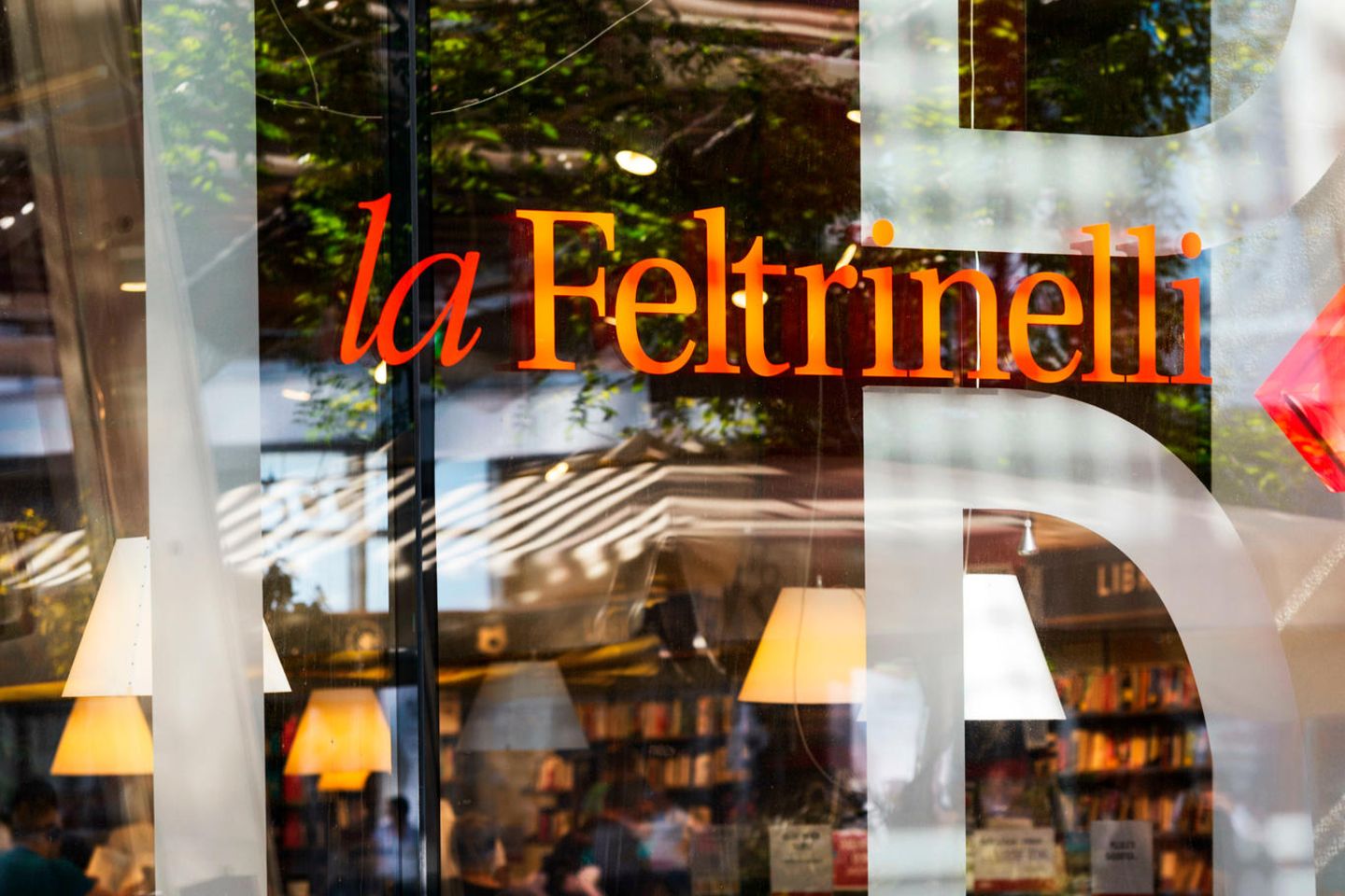 Casa Feltrinelli, Mailand Blick durchs Schaufenster, Menschen trinken Kaffee, dahinter Buchregale