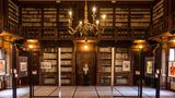 Holzregale voller Bücher über zwei Etagen mit Galerie, in der Mitte eine Büste
