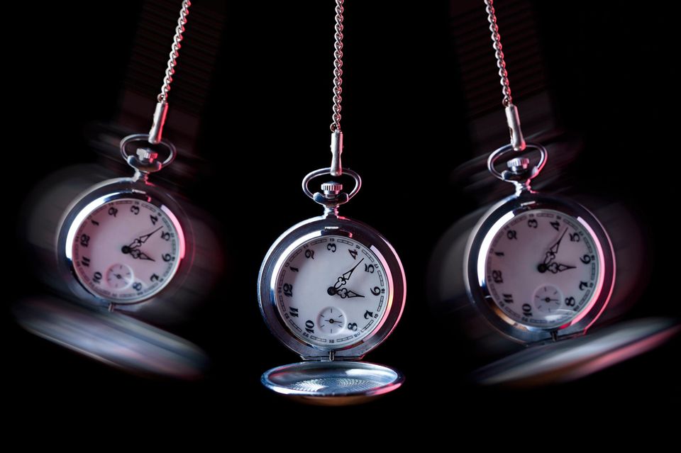 Eine pendelnde Uhr vor schwarzem Hintergrund 1.5004