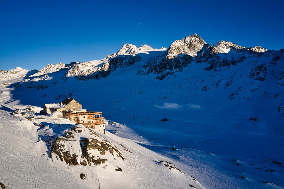 Almhütte umringt von schneebedeckter Landschaft und Bergmassiv