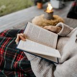 Frau liest ein Buch auf der Terrasse im Herbst