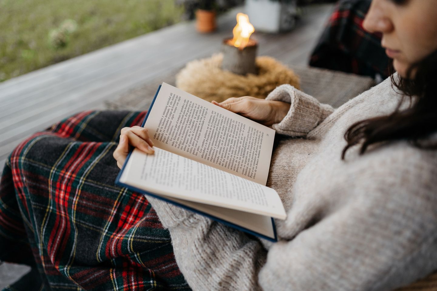 Frau liest ein Buch auf der Terrasse im Herbst