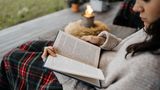 Frau liest ein Buch auf der Terrasse im Herbst