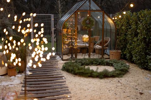 winterlicher Garten mit Glashaus und Weihnachtsdekoration am Abend