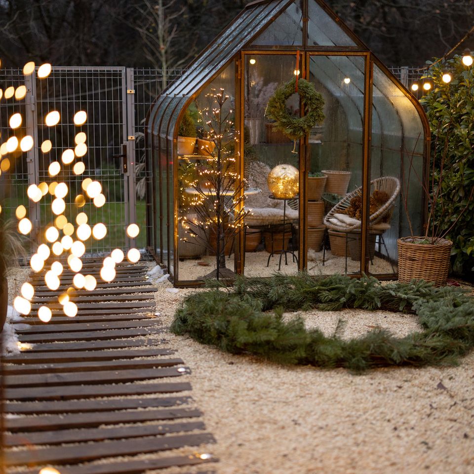 winterlicher Garten mit Glashaus und Weihnachtsdekoration am Abend