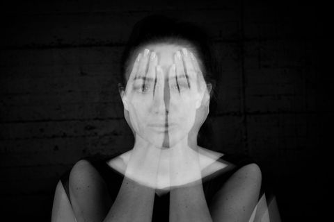 Schwarzweißfotografie, Mehrfachbelichtung: Porträt einer jungen Frau, die ihre durchscheinenden Hände vors Gesicht hält.