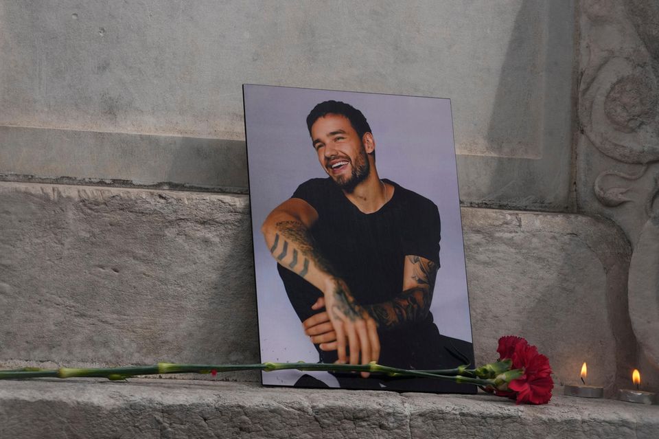 Parasoziale Trauer: Ein ausgedrucktes Foto des verstorbenen Liam Payne mit einer Blume und zwei angezündeten Kerzen davor. 1.5004