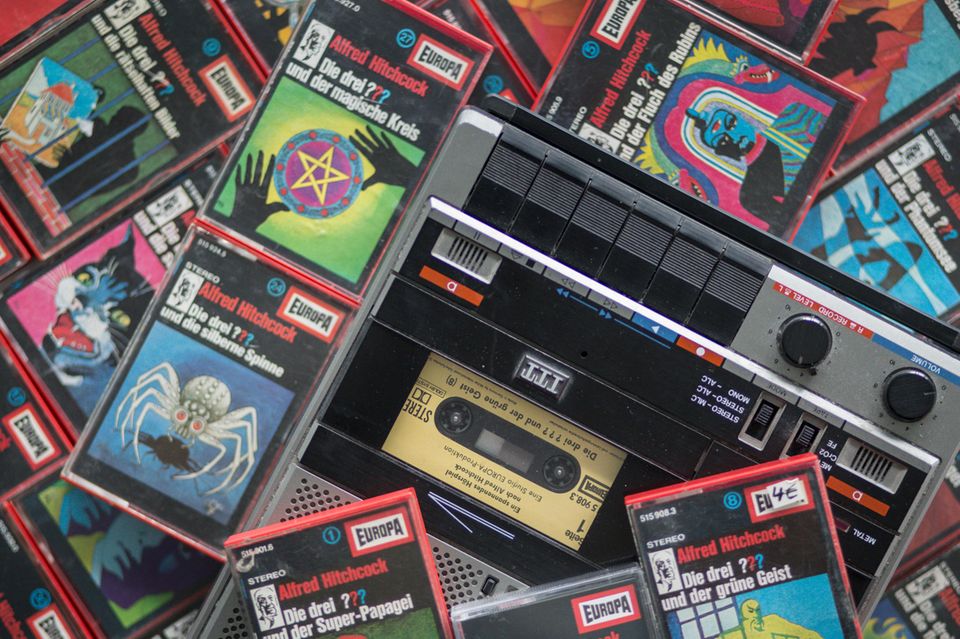 Bunte Kassetten der Hörspielserie "Die drei ???" liegen neben und auf einem Kassettenrekorder 1.5004