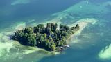 Luftaufnahme auf eine bewaldete Insel im See