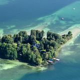 Luftaufnahme auf eine bewaldete Insel im See