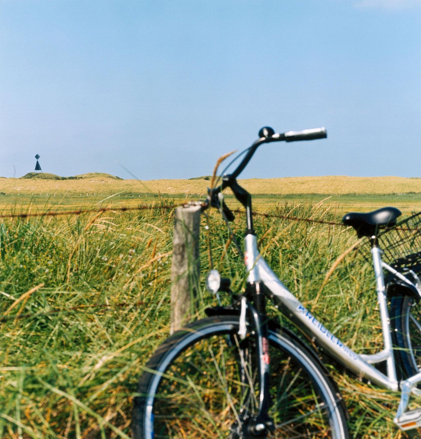 Fahrrad lehnt am Zaun eines Feldes