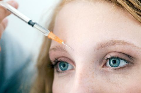 Nahaufnahme der Stirn einer jungen Frau, die eine Botoxspritze bekommt