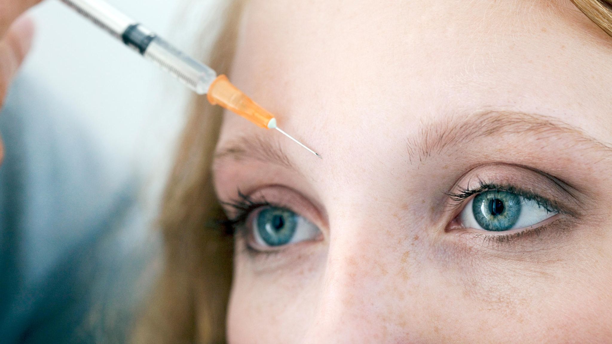 Nahaufnahme der Stirn einer jungen Frau, die eine Botoxspritze bekommt