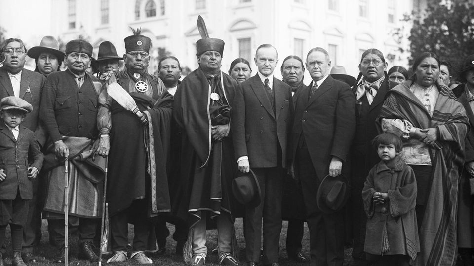 Im Garten des Weißen Hauses posiert 1924 eine Delegation der Osage mit US-Präsident Calvin Coolidge. Zeitweise haben die Indigenen das höchste Pro-Kopf-Einkommen der Welt 