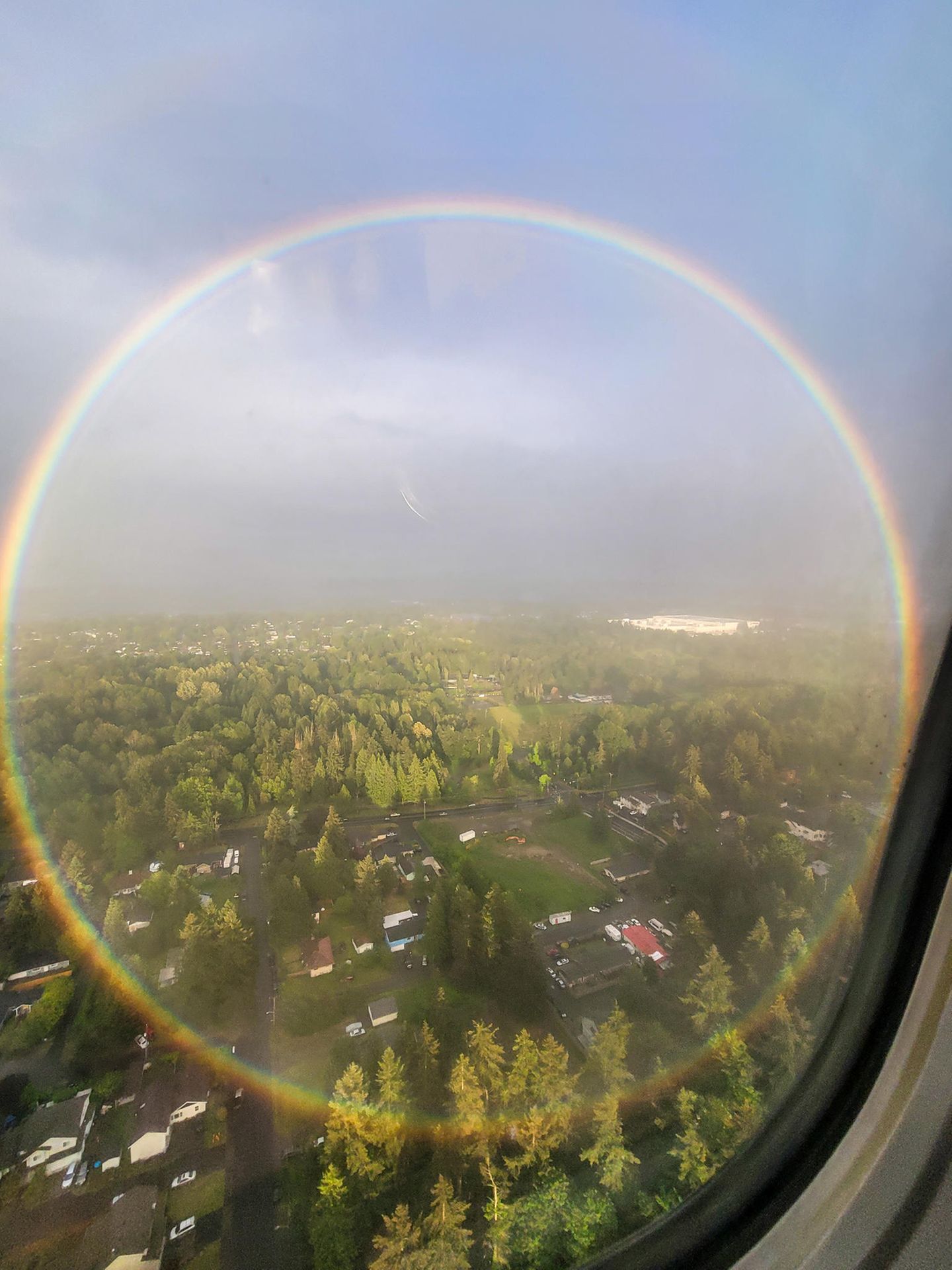 Die Welt ist eine Scheibe Ein kreisrunder Regenbogen über einer Häuseransammlung