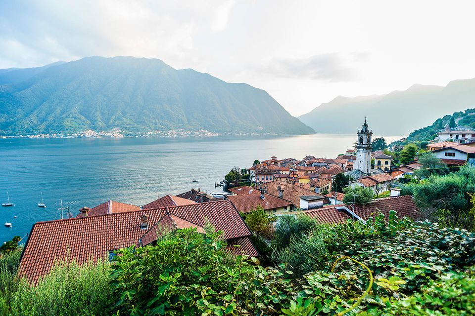 Dorf am See mit Bergen im Hintergrund