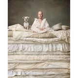 Ein Mädchen mit einer Glatze sitzt mit ihrem kleinen Hund auf einem Matratzenberg