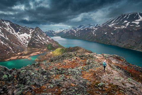 Woman hiking along turquoise and blue lakes in mountain landscape on hike of Knutshoe in Jotunheimen