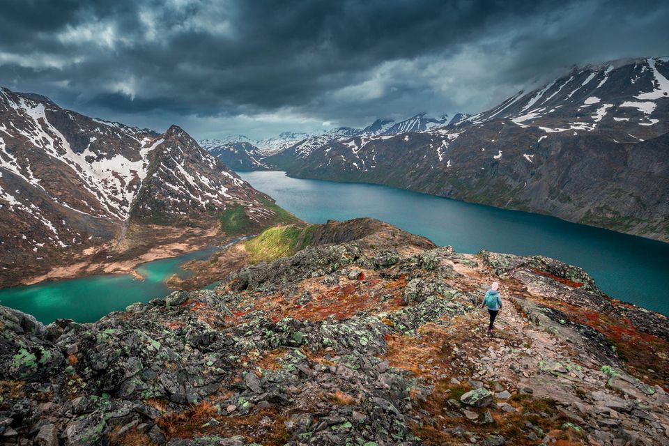 Woman hiking along turquoise and blue lakes in mountain landscape on hike of Knutshoe in Jotunheimen 1.7778