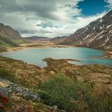 Turquoise lake surrounded by mountain landscape at Knutshoe summit in Jotunheimen National Park in Norway