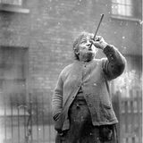 Frau schießt mit einem Pusterohr Erbsen gegen Fensterscheibe