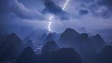 Power of Nature  Eigentlich hatte Kelvin Yuen ein ganz anderes Motiv im Sinn: Er wollte den friedlichen Sonnenaufgang über den Bergen der chinesischen Karstlandschaft in der Nähe von Guilin einfangen. Als er um drei Uhr morgens aufstand und den Berg erklomm, braute sich allerdings wie aus dem Nichts ein enormes Gewitter zusammen. Er ließ seine Drohne steigen und konnte damit die dramatische Kraft der Natur in einem ganz besonderen Panorama festhalten. Diese spektakuläre Aufnahme sicherte ihm sowohl den Sieg als "Photograph des Jahres" als auch den ersten Platz in der Kategorie "Nature/Landscape".