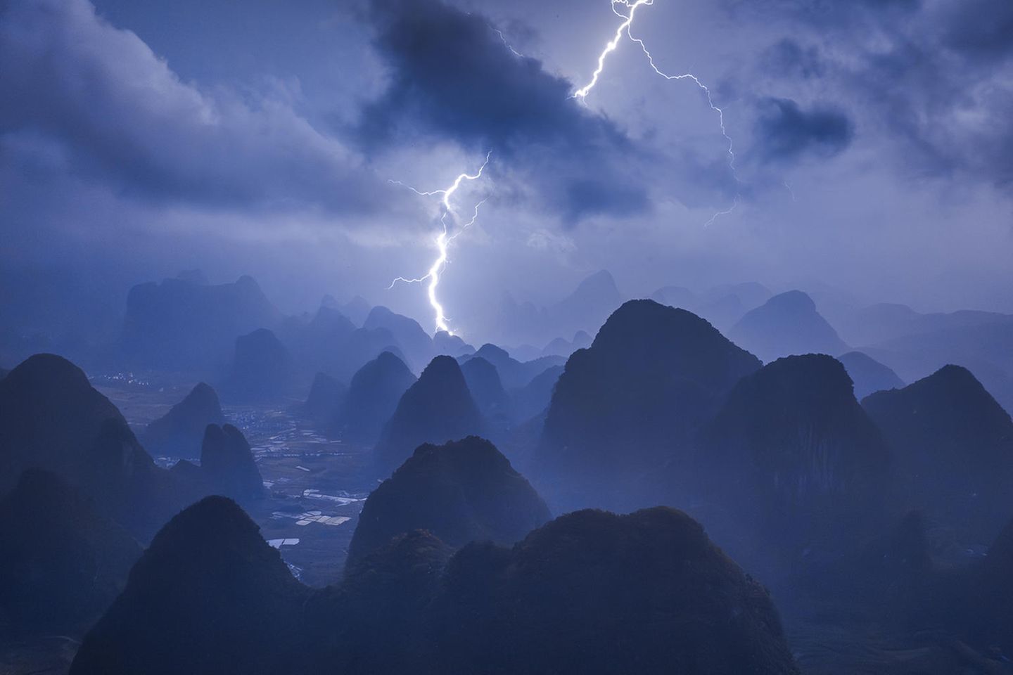 Power of Nature  Eigentlich hatte Kelvin Yuen ein ganz anderes Motiv im Sinn: Er wollte den friedlichen Sonnenaufgang über den Bergen der chinesischen Karstlandschaft in der Nähe von Guilin einfangen. Als er um drei Uhr morgens aufstand und den Berg erklomm, braute sich allerdings wie aus dem Nichts ein enormes Gewitter zusammen. Er ließ seine Drohne steigen und konnte damit die dramatische Kraft der Natur in einem ganz besonderen Panorama festhalten. Diese spektakuläre Aufnahme sicherte ihm sowohl den Sieg als "Photograph des Jahres" als auch den ersten Platz in der Kategorie "Nature/Landscape".