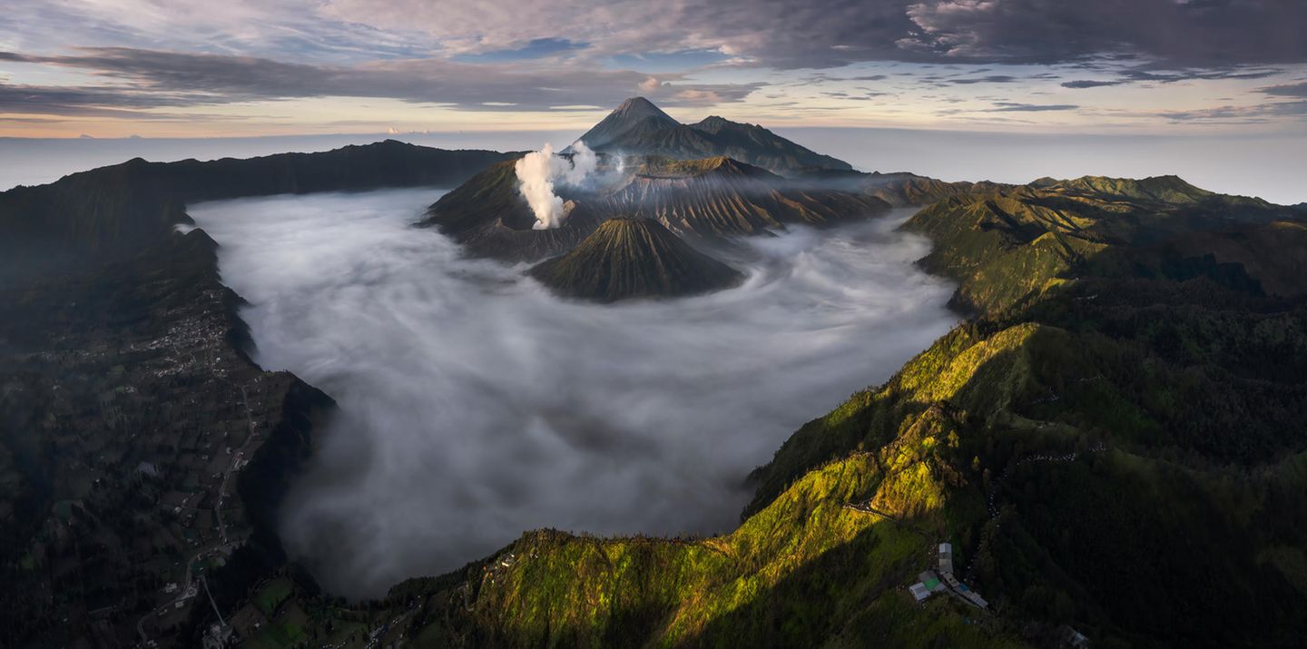 The Volcanoes Theatre  Bei Sonnenaufgang wabern Nebelschwaden träge im Krater des Vulkans Bromo auf der indonesischen Insel Java. Als einer der aktivsten Vulkane auf Java ist der 2329 Meter hohe Berg ein beliebtes Touristenziel im Nationalpark Bromo-Tengger-Semeru. Die Fotografin Fikri Muharom gewann mit ihrer 180°-Drohnenaufnahme der Vulkankette den ersten Preis in der Kategorie "Southeast Asia Open Photographer of the Year". 