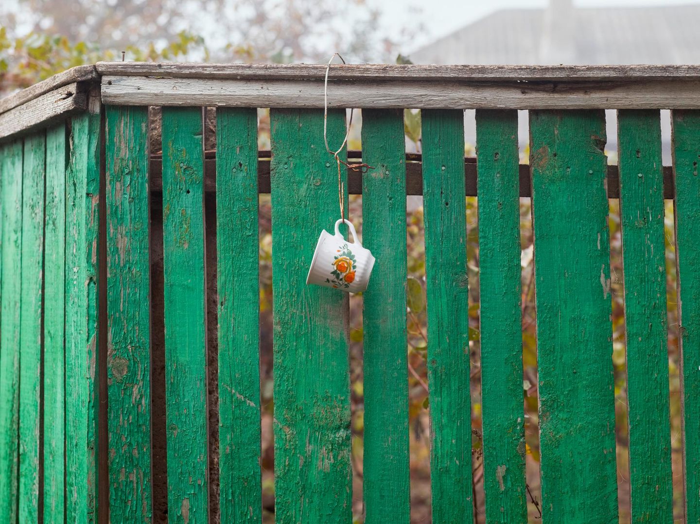 Tasse am Gartenzaun, um bei der Gartenarbeit Wasser aus dem Brunnen trinken zu können