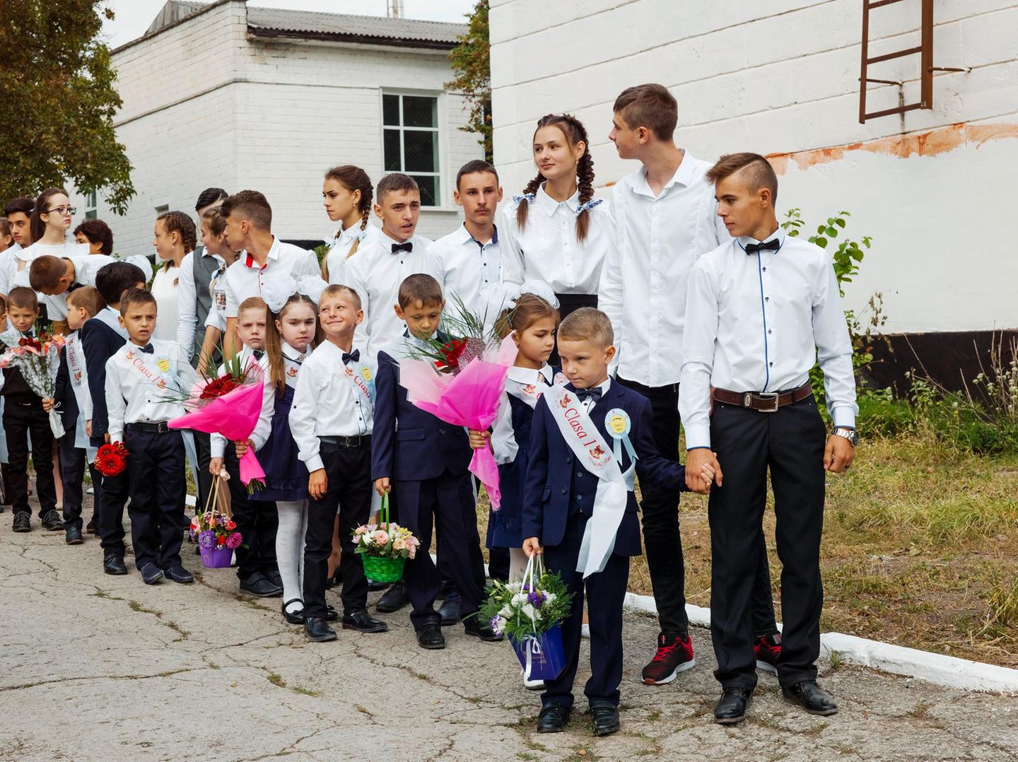 Eine Gruppe Schüler mit Erstklässlern, die Blumensträuße in den Händen halten
