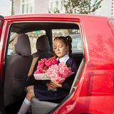 Tochter des Bürgermeisters sitzt mit Blumenstrauß in der Hand in rotem Auto