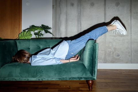 Eine Frau liegt mit dem Gesicht nach unten auf einer Couch