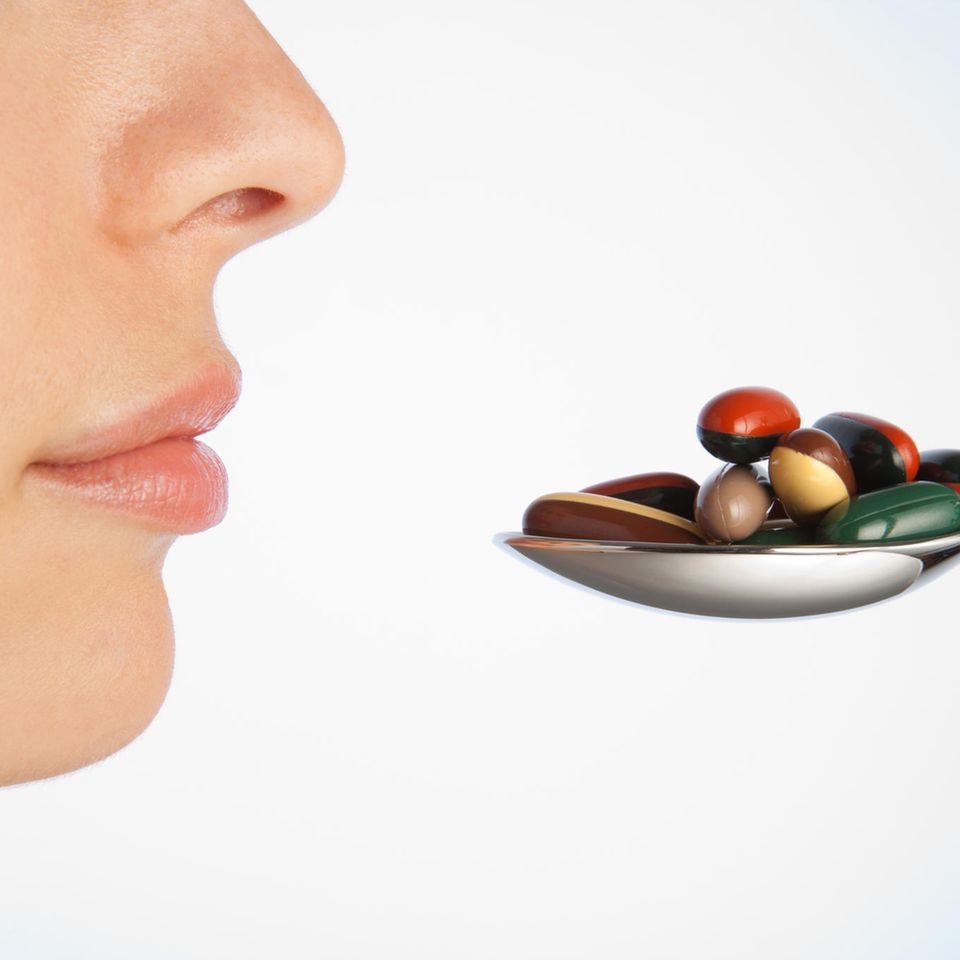 Auf einem Löffel liegen bunte Tabletten