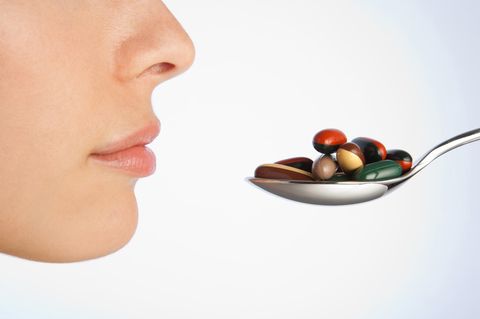 Auf einem Löffel liegen bunte Tabletten