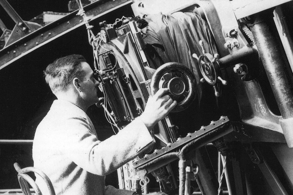 Edwin Hubble sitzt auf einem Stuhl und benutzt das 100 inch Hooker Teleskop