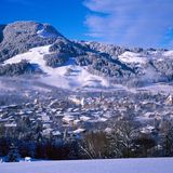 Verschneiter Hang mit Abfahrt, unten die Stadt