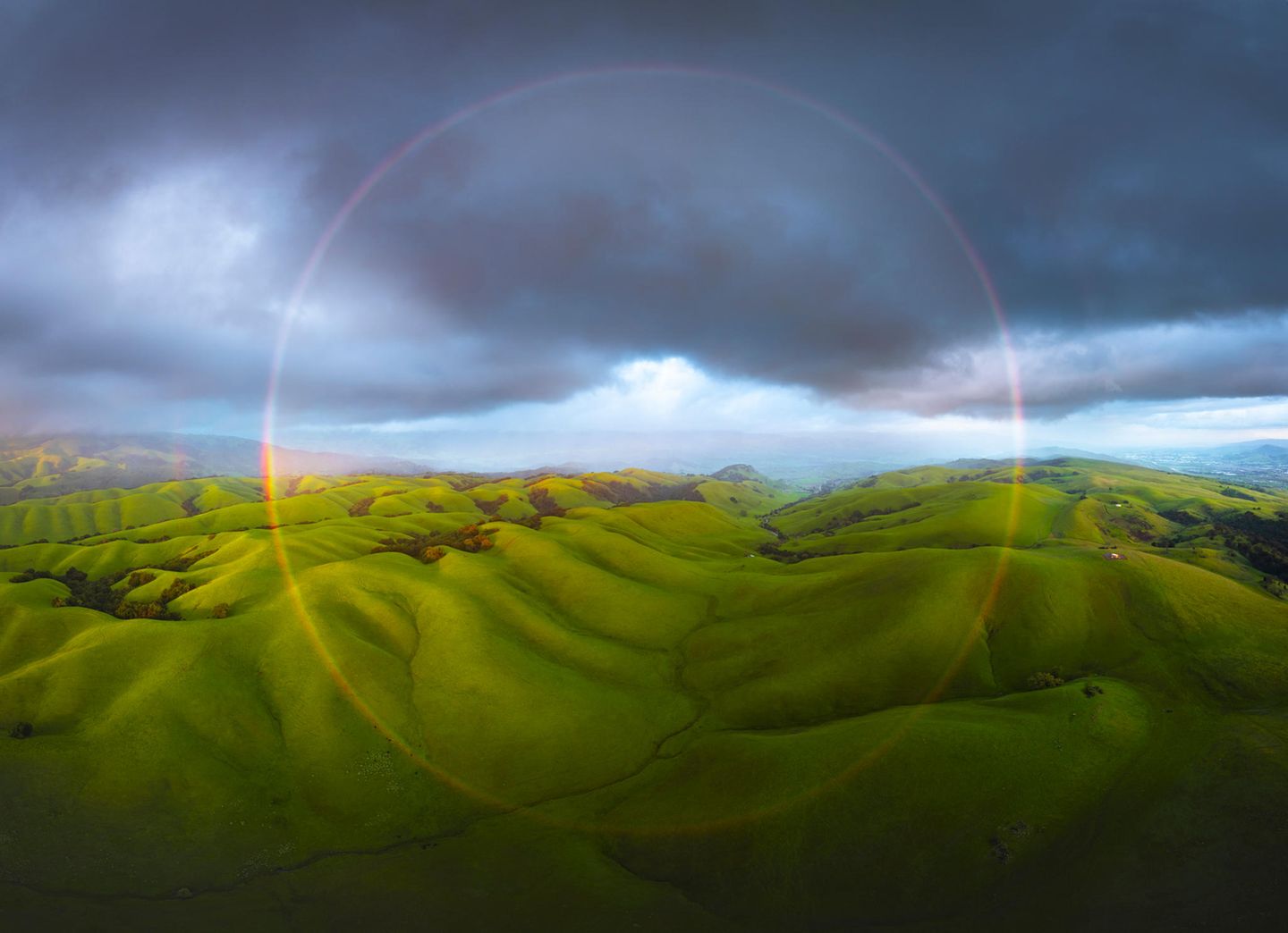 Weite grüne, hügelige Landschaft mit Wolken am Horizont
